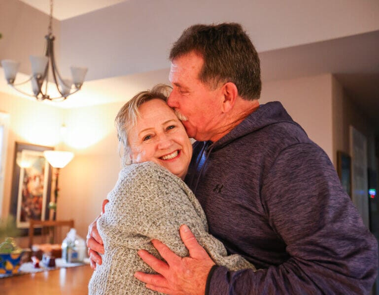 Priscilla and Tim McGinley embrace, as Tim kisses his wife on the side of her head