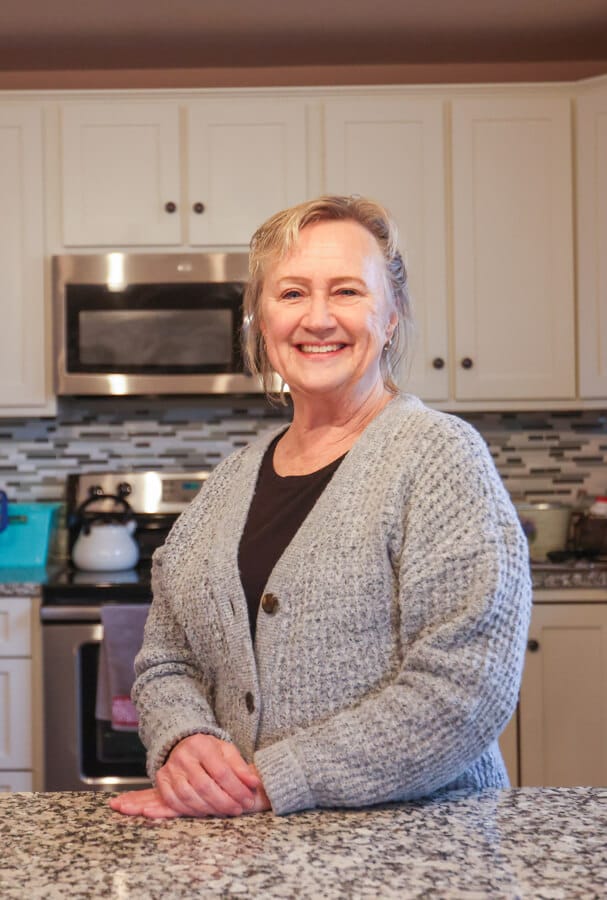 Priscilla McGinley standing in her home kitchen, smiling