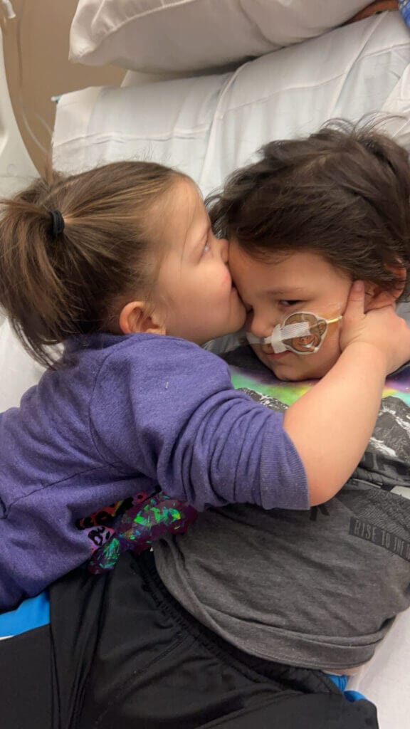 A sister consoles her brother with a kiss on the head