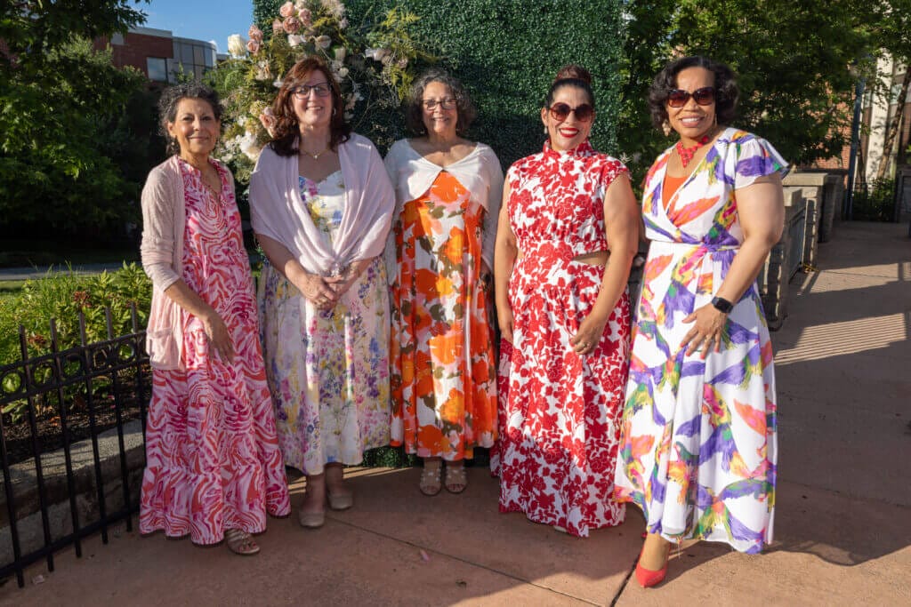 Gala attendees wearing dresses and smiling at the camera