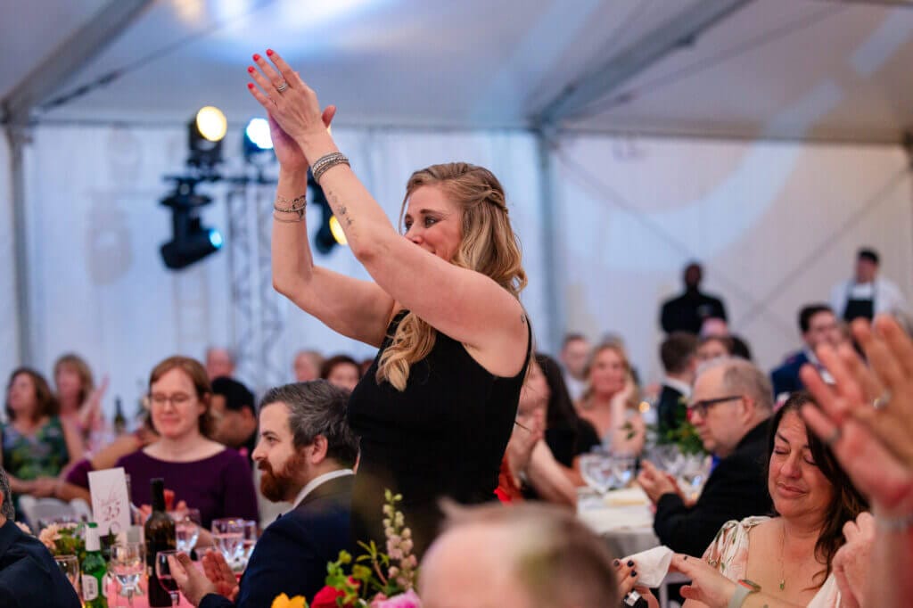 An individual stands up and claps in the tent