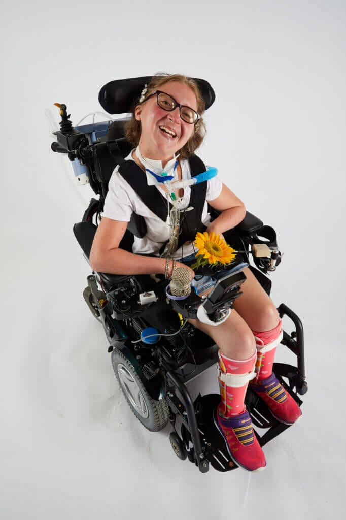 long-term care resident in a power wheelchair smiles at the camera