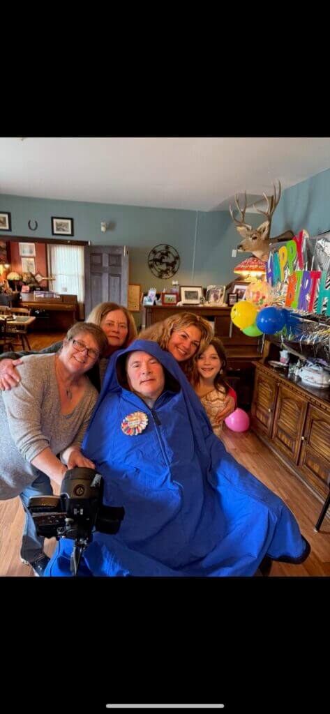 A family of five gathers and poses for a photo, smiling at the camera